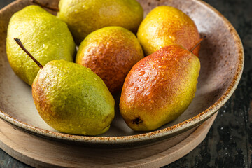 ripe pears in a bowl on a wooden background
