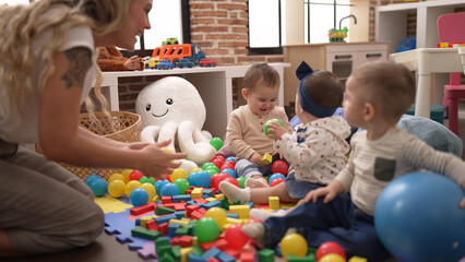 Teacher and preschool students playing with balls sitting on floor at kindergarten