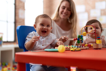 Teacher and preschool students playing with toys sitting on table at kindergarten