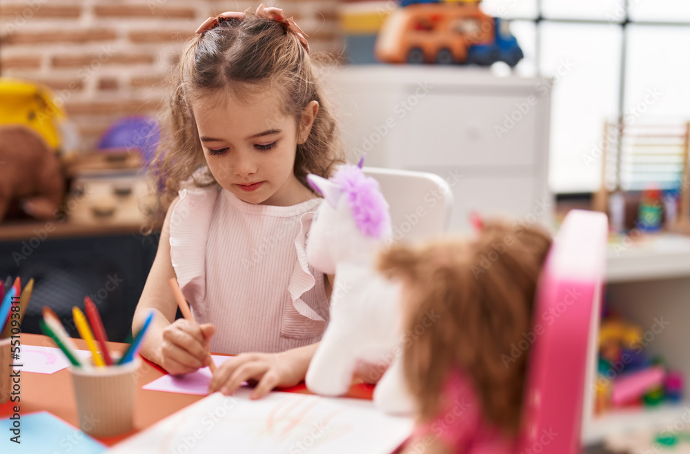 Poster adorable caucasian girl student sitting on table drawing on paper at classroom