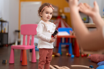 Adorable caucasian girl smiling confident holding car toy at kindergarten