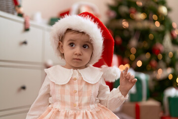 Adorable caucasian girl standing by christmas tree at home