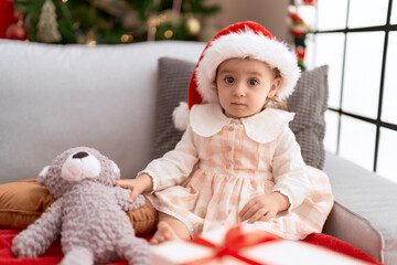 Adorable caucasian girl sitting on sofa by christmas tree at home
