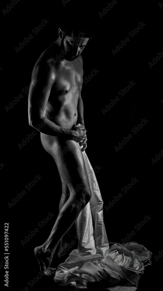 Sticker Grayscale shot of Nude male fitness model covering himself with sheet against black background