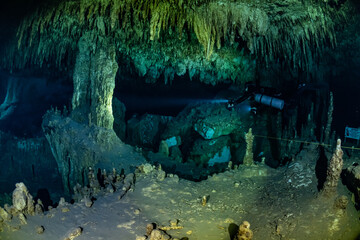 Fototapeta premium cave diver instructor leading a group of divers in a mexican cenote underwater