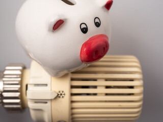 Piggy bank on a heating radiator with a temperature regulator.