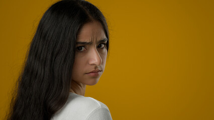 Portrait in yellow studio sad upset stressed Indian ethnic woman suffer with anxiety female anxious face depressed girl worry with depression despair lady desperate model problem looking at camera