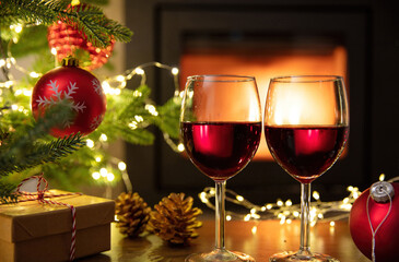 Red wine and Christmas decoration on table, fireplace background. Xmas celebration