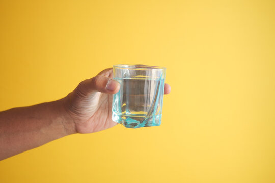 Holding A Glass Of Water Against Yellow Background 