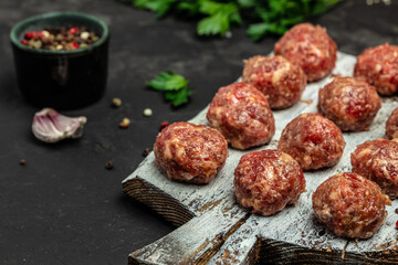 Fresh raw beef meatballs with spices on a cutting board on a dark background, banner, menu, recipe place for text, top view