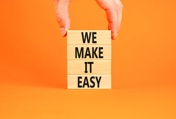 We make it easy symbol. Concept words We make it easy on wooden cubes. Beautiful orange table orange background. Businessman hand. Business motivational we make it easy concept. Copy space.