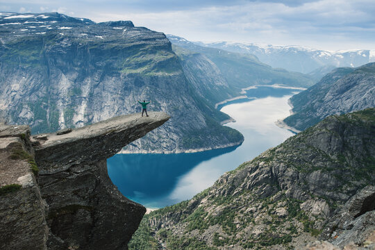 A person standing on the reef called trolltunga looking at the breathtaking view on norway lake and mountains. Norway famous place. Summer hiking. 