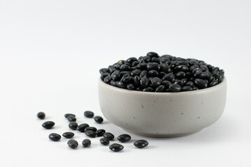 Fototapeta na wymiar Black beans in a gray ceramic bowl on a white background.