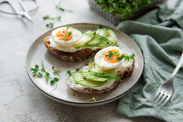 Bread toast, boiled eggs, avocado slice, microgreens on a plate