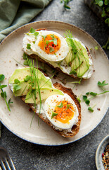 Bread toast, boiled eggs, avocado slice, microgreens on a plate