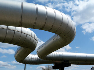 overhead steel pipeline. aluminum shroud covered gas or heating supply tubes on concrete support....