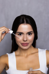 Obraz premium Portrait of young woman applying hyaluronic acid at home. Skin care routine.