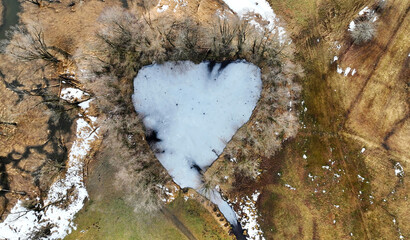 Luftaufnahme mit einer Drohne von einem zugefrorenen See mit Herzform in Bayern