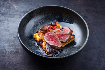 Traditional roasted Italian panettone tagliata di manzo with sliced beef steak and vegetable served as close-up on a Nordic design plate