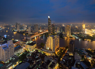 Aerial view of Bangkok City skyline by Chao Phraya River in Thailand. Financial district and skyscraper office buildings. Downtown skyline. Urban town at sunset.