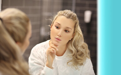 Woman looking in the mirror Applying the cream..Magic anti-aging cream