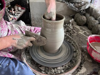  working in a pottery studio throwing a pot.