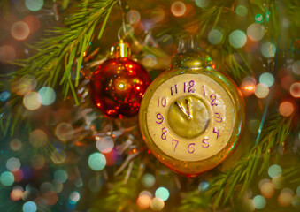 The arrows of the Christmas toy in the form of a clock on the festive tree show the time 23.55