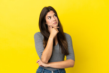 Young Brazilian woman isolated on yellow background having doubts