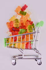 Gummy bears in a small supermarket basket on a white background.

