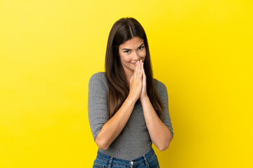 Young Brazilian woman isolated on yellow background keeps palm together. Person asks for something