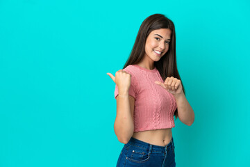 Young Brazilian woman isolated on blue background pointing to the side to present a product