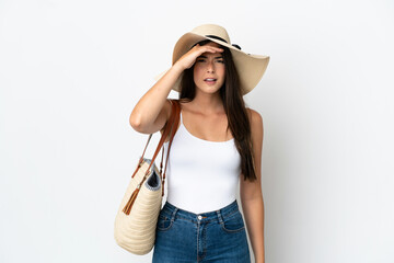 Young Brazilian woman with Pamela holding a beach bag isolated on white background looking far away with hand to look something