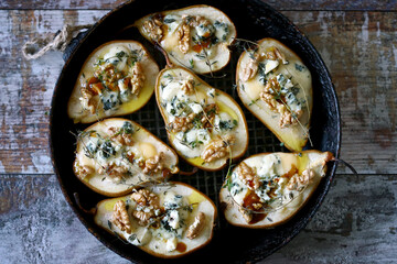 Baked pears with dor blue cheese, honey, thyme and walnuts. French style kitchen.