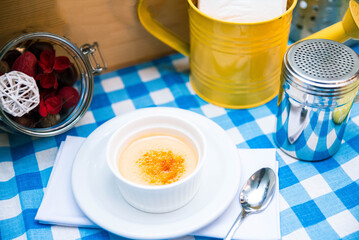 portion of delicate creme brulee with crust in ramekin on the table on a checkered napkin