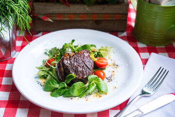 Beef steak chateaubriand with corn salad and arugula leaves, cherry tomato slices, olive oil