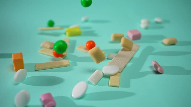multicolored chewing candies gum falling in slow mo on a blue background