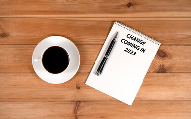 a cup of coffee and a notepad with pens on a wooden background