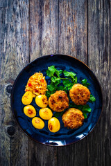 Fried pork meatballs with fried potatoes and cabbage on wooden table
