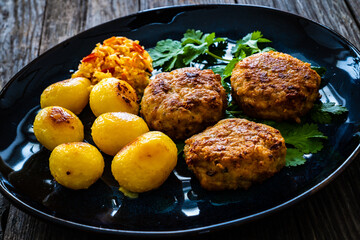 Fried pork meatballs with fried potatoes and cabbage on wooden table
