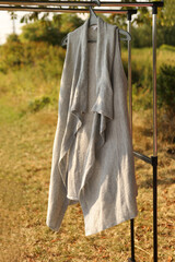 A gray sleeveless sweater hangs on a hanger.