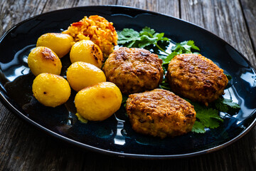 Fried pork meatballs with fried potatoes and cabbage on wooden table
