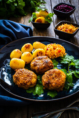Fried pork meatballs with fried potatoes and cabbage on wooden table
