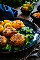 Fried pork meatballs with fried potatoes and cabbage on wooden table
