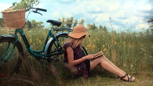 woman sitting on flower meadow and reading book diary
