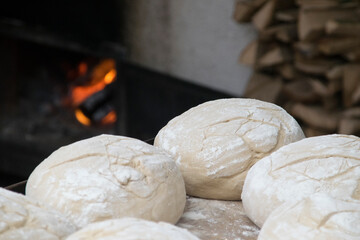 Zu backende Brotlaibe vor dem Ofen mit Holzscheiten