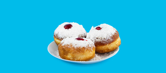 Jewish holiday Hanukkah concept. Plate with donut sufganiyot with sugar powder and jam on a blue background.