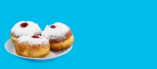 Jewish holiday Hanukkah concept. Plate with donut sufganiyot with sugar powder and jam on a blue background.