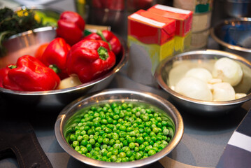 A set of raw food ingredients before making dinner. Fresh green peas, ripe red bell peppers, onions.