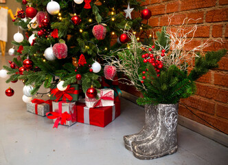 Gifts under the Christmas tree and pine branches with berries in cement boots