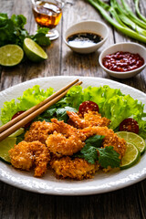 Fried panko prawns with lime, tomatoes and greens wooden table
